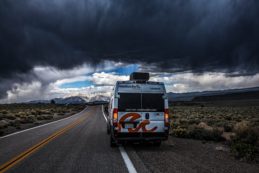 Wohnmobil auf einsamem Highway unter einer dunklen Gewitterfront in Nevada.
