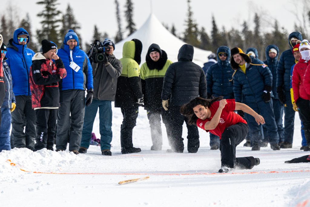 Athlet bei einem traditionellen Wettbewerb der Arctic Winter Games im Schnee.