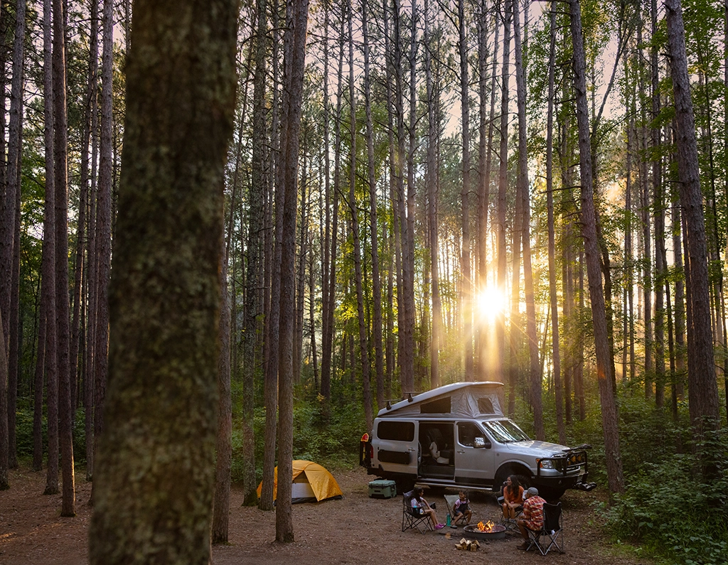 Familie beim Camping mit Campervan, Zelt und Lagerfeuer im Chippewa National Forest in Minnesota.