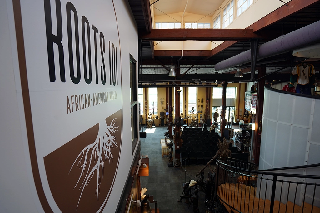 Roots-101-Logo und Blick vom Obergeschoss in die Haupthalle des African American Museum in Louisville.