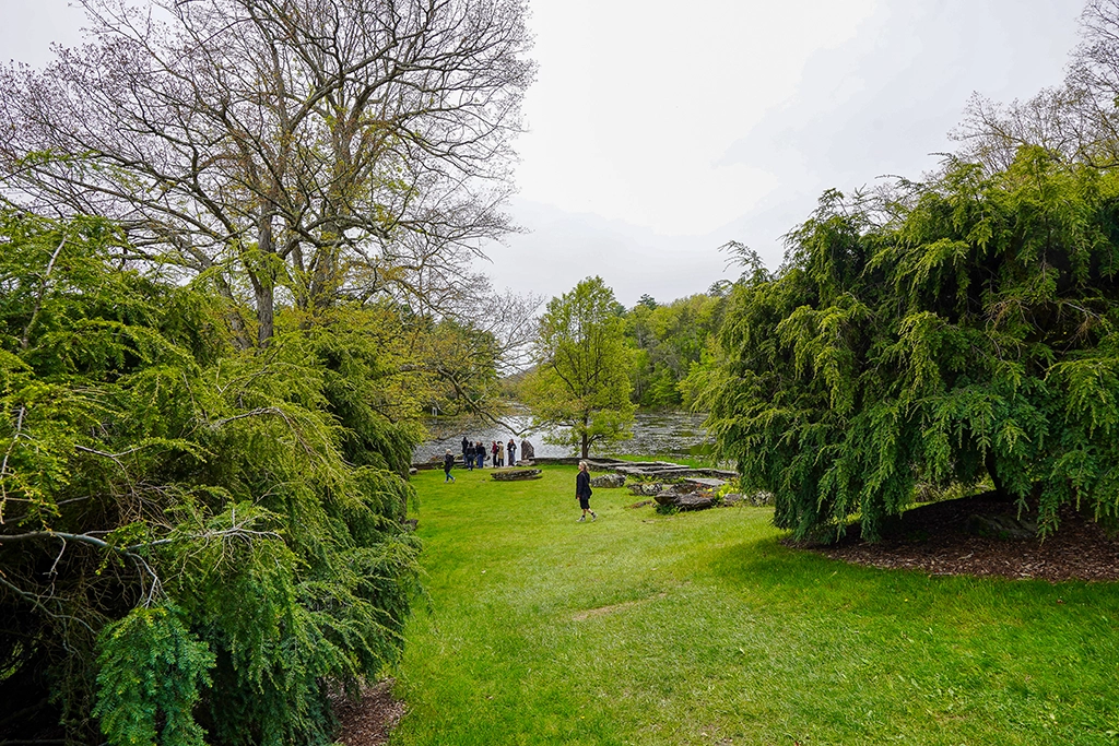 Große Rasenfläche mit Solitärgehölzen und Besuchern am Tyrrel Lake im Innisfree Garden.