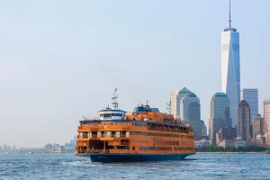 Orange Staten Island Ferry auf dem New Yorker Hafen vor der Skyline von Lower Manhattan und dem One World Trade Center.
