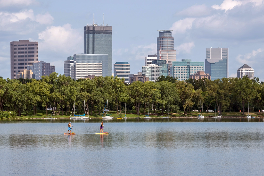 Stand-up-Paddler auf dem Bde Maka Ska mit der Skyline von Minneapolis im Hintergrund.
