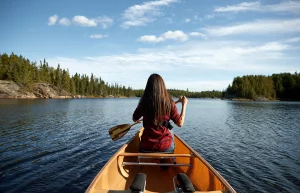 Kanufahrerin auf einem von Wäldern umgebenen See in der Boundary Waters Canoe Area Wilderness in Minnesota.