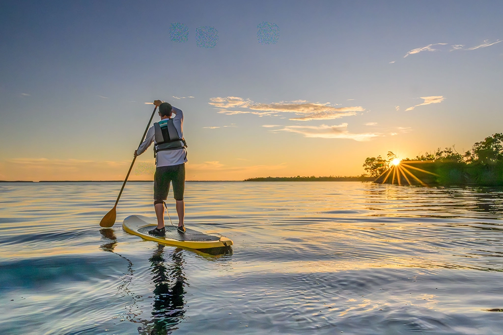 Stand-up-Paddler auf ruhigem Wasser bei Sonnenuntergang an der Golfküste von Fort Myers.