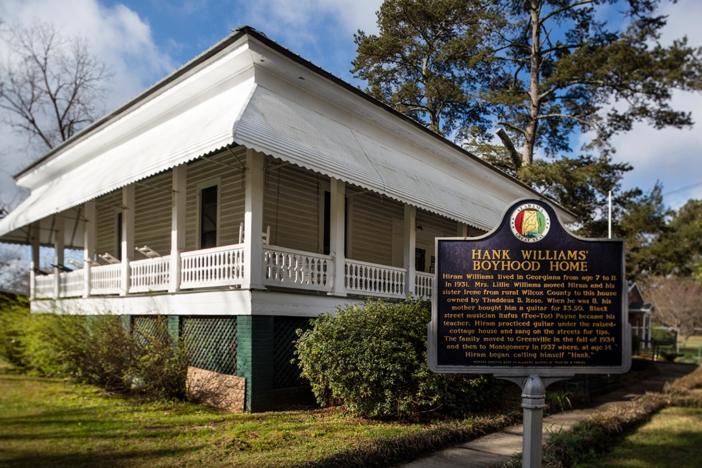 Hank Williams’ Boyhood Home in Georgiana, Alabama, mit historischem Hinweisschild vor dem weißen Holzhaus.