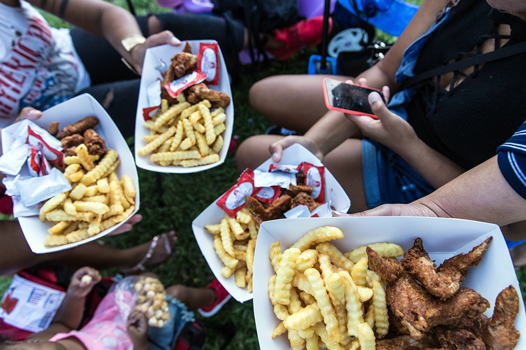 Besucher mit Fried Chicken und Pommes beim National Fried Chicken Festival in New Orleans