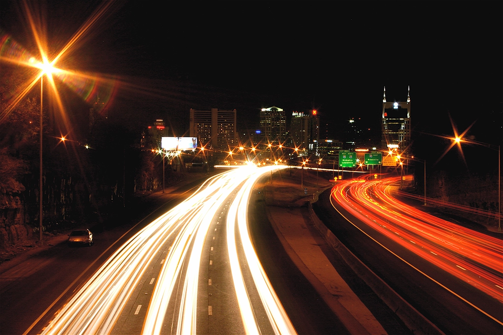 Interstate 65 bei Nacht mit Lichtspuren des Verkehrs und der beleuchteten Skyline von Nashville im Hintergrund.