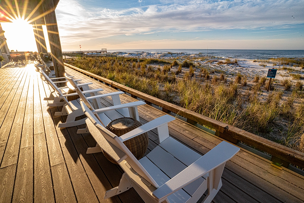 Adirondack-Stühle auf der Terrasse der Lodge at Gulf State Park mit Blick auf Dünen und den Golf von Mexiko in Gulf Shores, Alabama.
