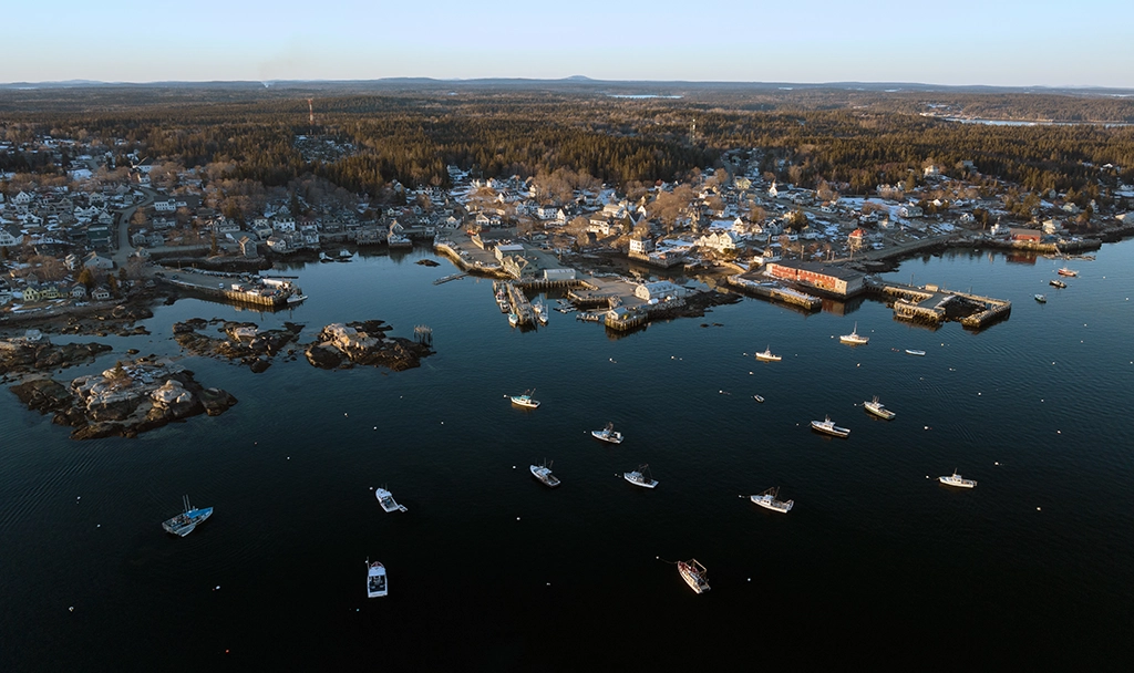 Luftaufnahme von Bar Harbor in Maine mit Hafen, Segelbooten und bewaldeter Küstenlandschaft im Spätwinter