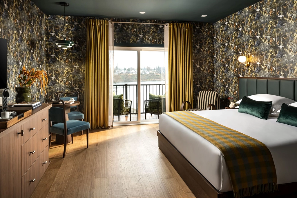 Elegantes Gästezimmer im Claramount Club in Picton, Ontario, mit floralen Tapeten, Doppelbett und Balkon mit Wasserblick