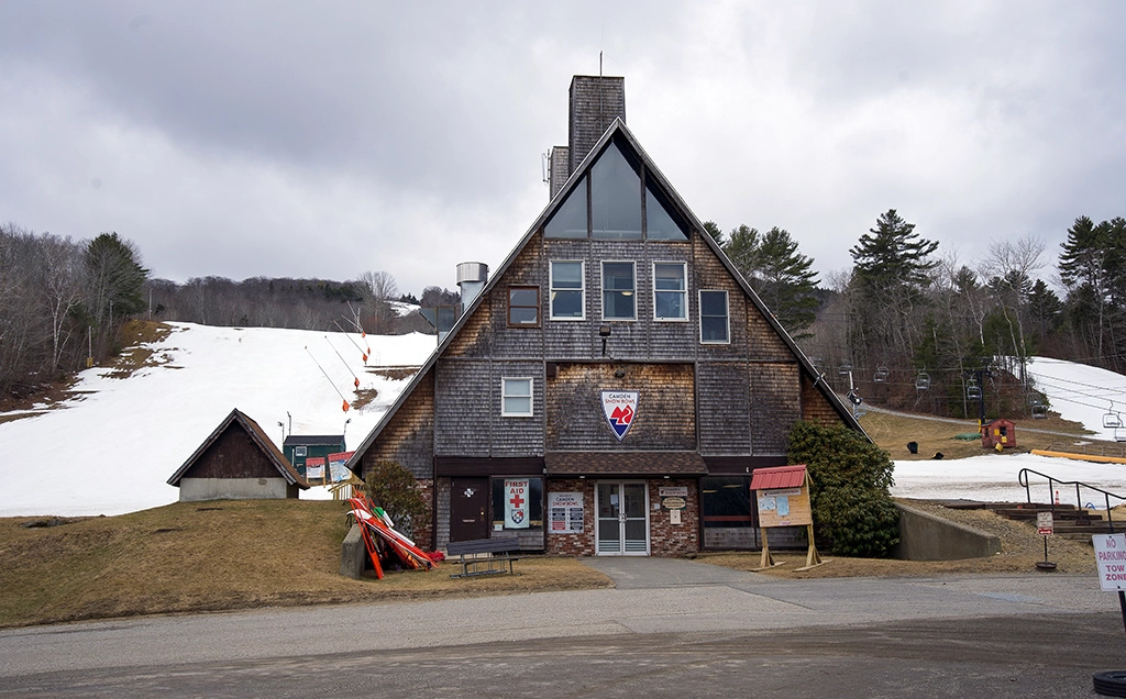 Base Lodge der Camden Snow Bowl in Maine mit markantem Spitzdach, teilweise schneebedeckten Skipisten und Sessellift am Ragged Mountain.