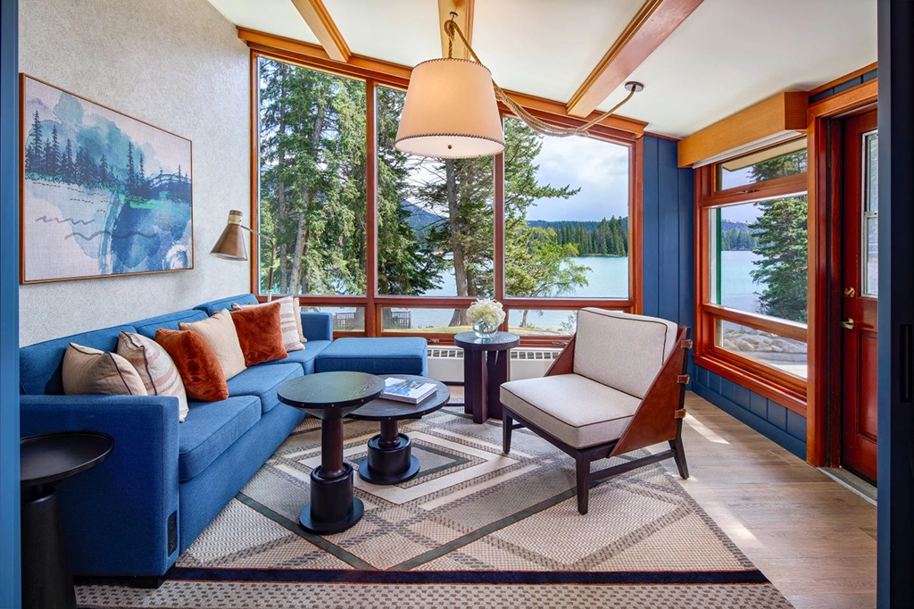 Modernisierte Junior Suite mit blauer Sitzecke und großen Panoramafenstern zum Lac Beauvert in der Fairmont Jasper Park Lodge, Alberta