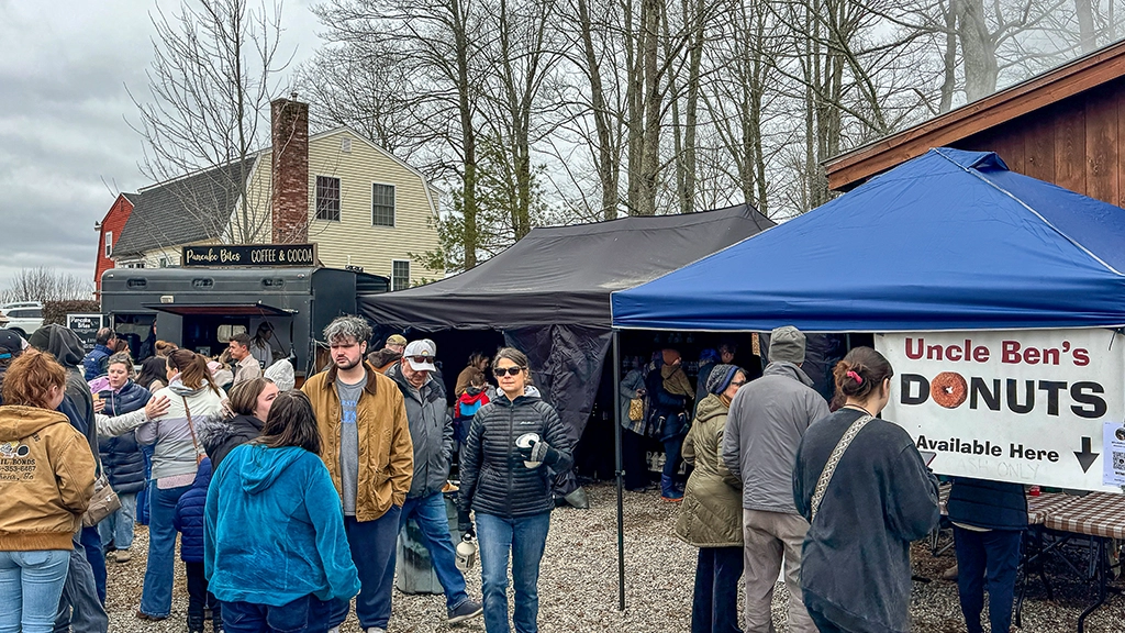 Besucher und Verkaufsstände mit Donuts, Kaffee und regionalen Spezialitäten beim Maine Maple Weekend auf der Harris Farm in Dayton