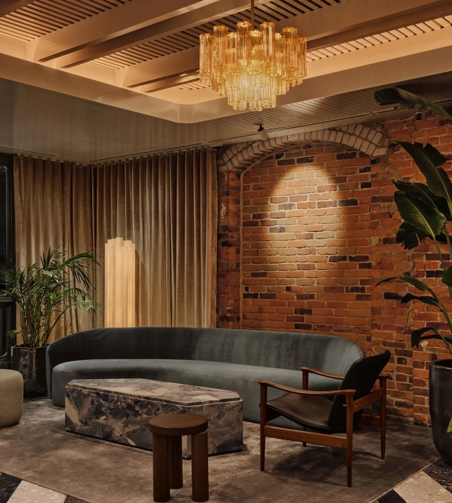 Eleganter Loungebereich im Hôtel Nelligan in Montréal mit freigelegten Backsteinwänden, Designmöbeln und einem großen Kronleuchter