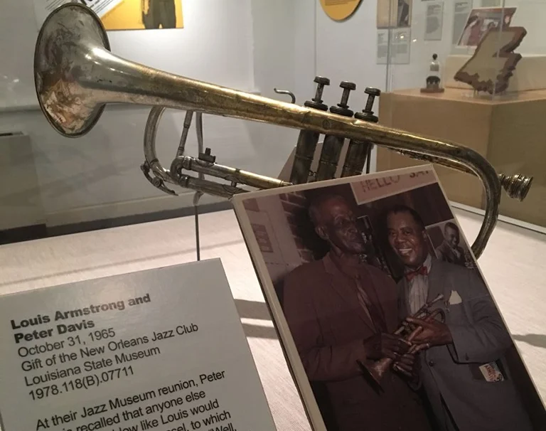 Trompete und historische Fotografie von Louis Armstrong und Peter Davis in einer Museumsausstellung über die Jazzgeschichte Louisianas.