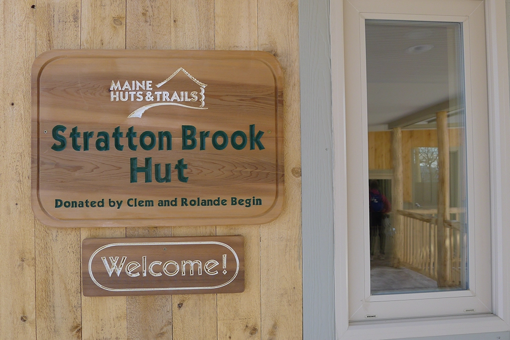 Holzschild am Eingang der Stratton Brook Hut von Maine Huts & Trails im Carrabassett Valley, Maine
