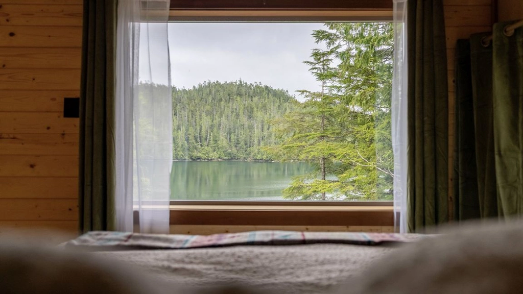 Blick aus einem Schlafzimmer der Wahous Wilderness Lodge auf eine bewaldete Bucht im Clayoquot Sound an der Westküste Vancouver Islands