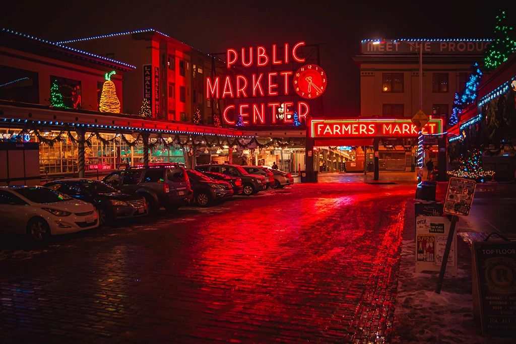 Pike Place Market in Seattle bei Nacht mit rot leuchtendem Public Market Center-Schriftzug und festlicher Weihnachtsbeleuchtung.